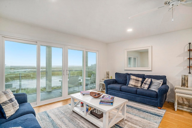 living room featuring a water view, ceiling fan, and light hardwood / wood-style flooring