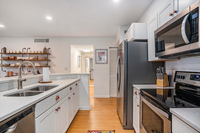 kitchen featuring stainless steel appliances, white cabinets, sink, and light hardwood / wood-style flooring