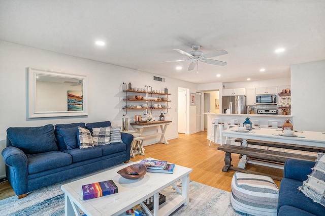 living room with ceiling fan and light hardwood / wood-style flooring