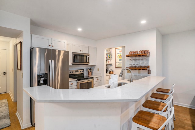 kitchen featuring white cabinetry, stainless steel appliances, sink, and a breakfast bar area