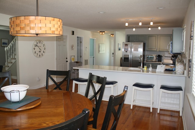 kitchen with kitchen peninsula, stainless steel appliances, backsplash, gray cabinets, and dark hardwood / wood-style flooring