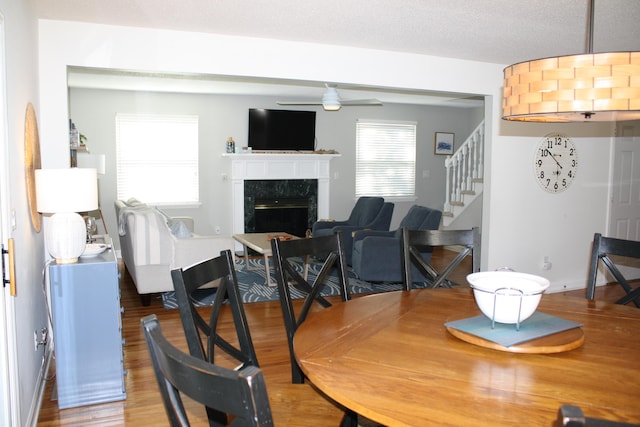 dining area with a premium fireplace, a textured ceiling, wood-type flooring, and ceiling fan