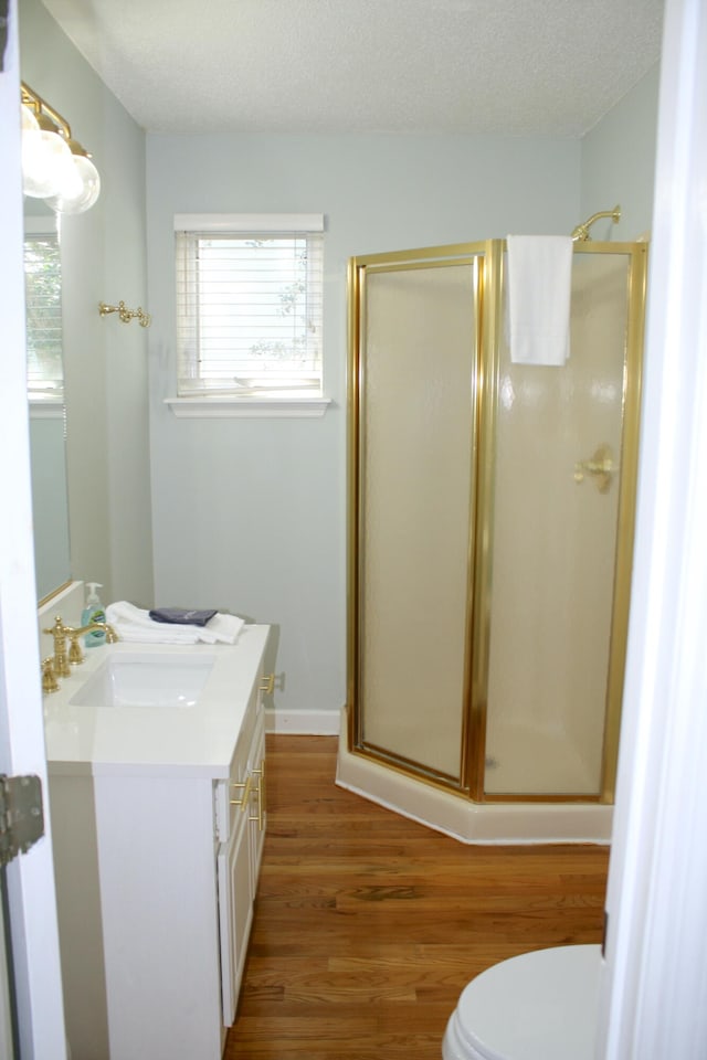 bathroom with toilet, wood-type flooring, vanity, a textured ceiling, and an enclosed shower