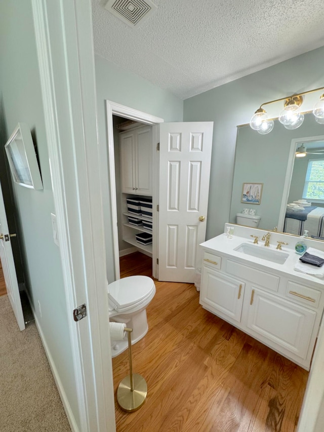 bathroom with vanity, a textured ceiling, wood-type flooring, and toilet