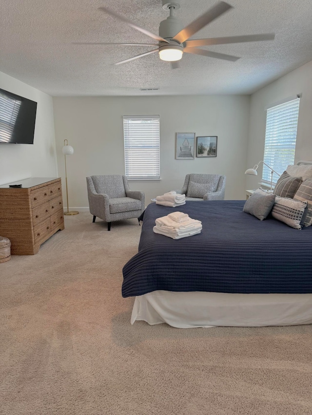 bedroom with light carpet, a textured ceiling, and ceiling fan