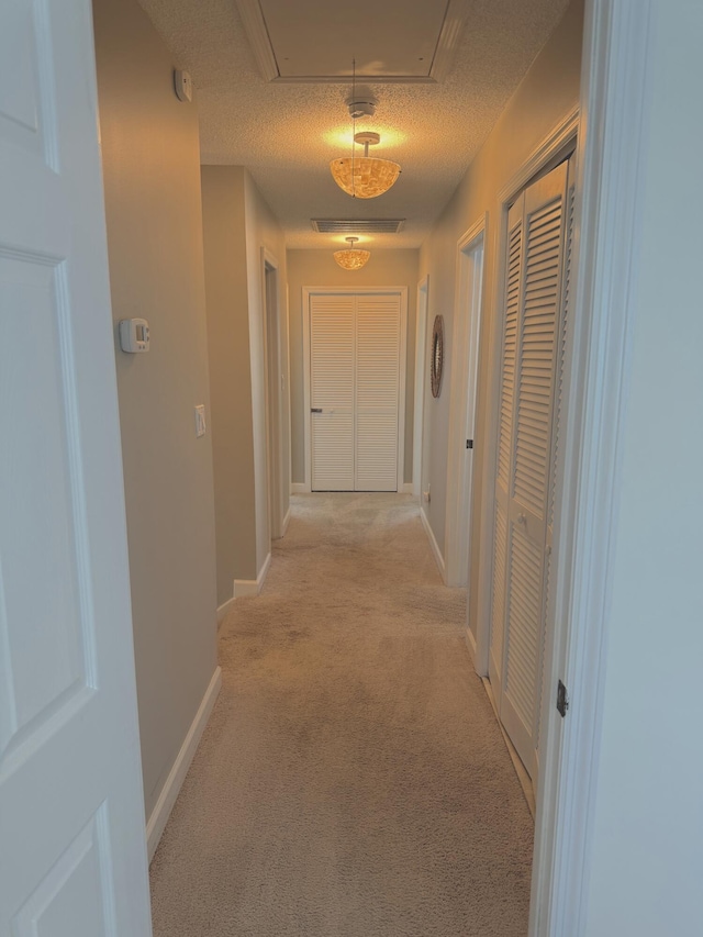 32 41st Ave, Isle Of Palms, SC 29451 - hallway with light colored carpet, attic access, baseboards, and a textured ceiling