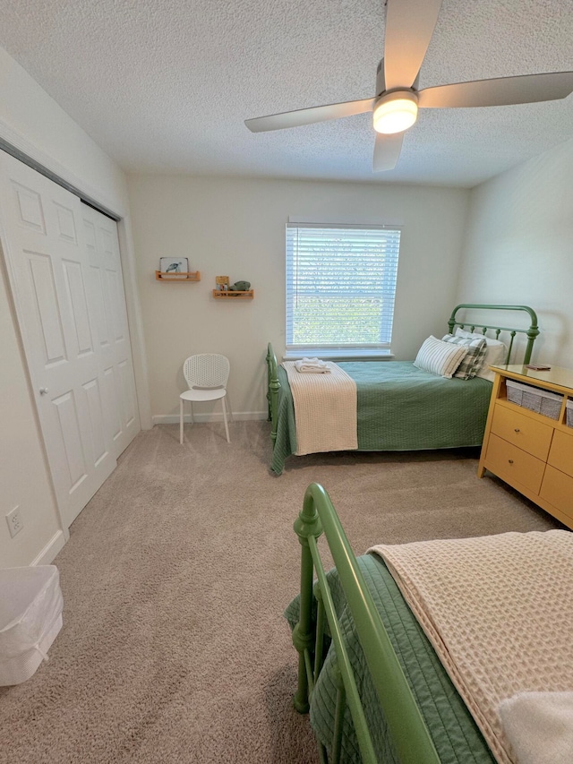 bedroom featuring light carpet, a closet, a textured ceiling, and ceiling fan