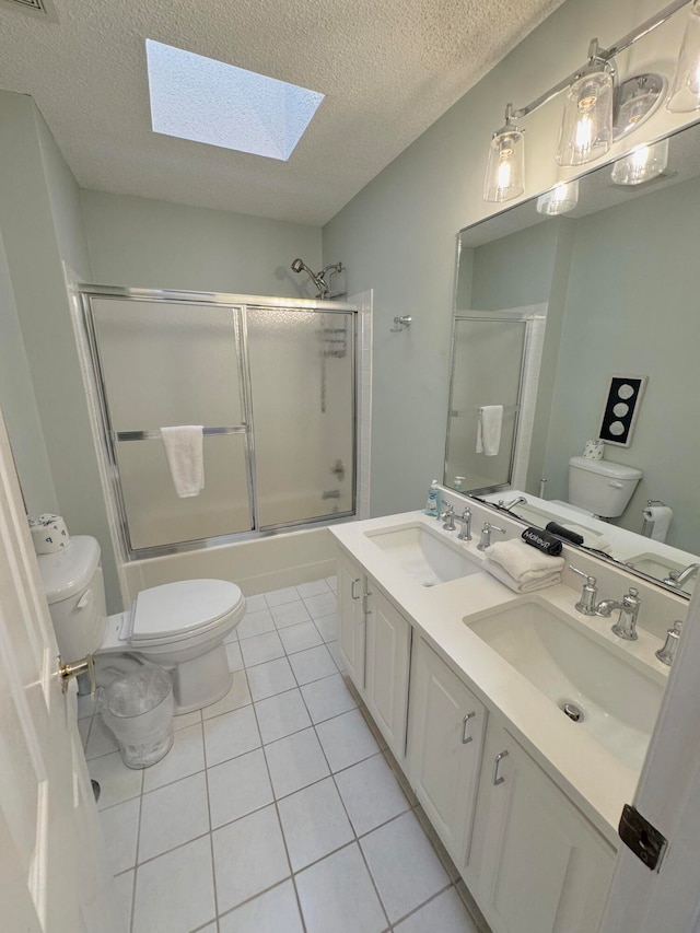 full bathroom featuring vanity, shower / bath combination with glass door, toilet, and tile patterned flooring