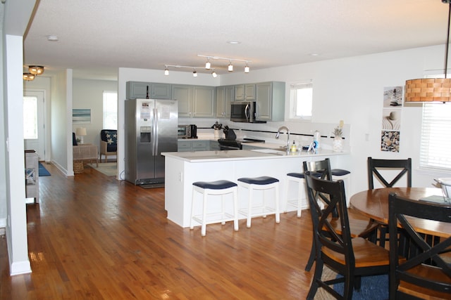 kitchen featuring stainless steel appliances, tasteful backsplash, dark hardwood / wood-style flooring, and kitchen peninsula