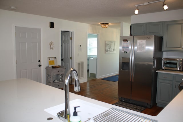 kitchen with stainless steel fridge, a textured ceiling, dark wood-type flooring, gray cabinetry, and sink