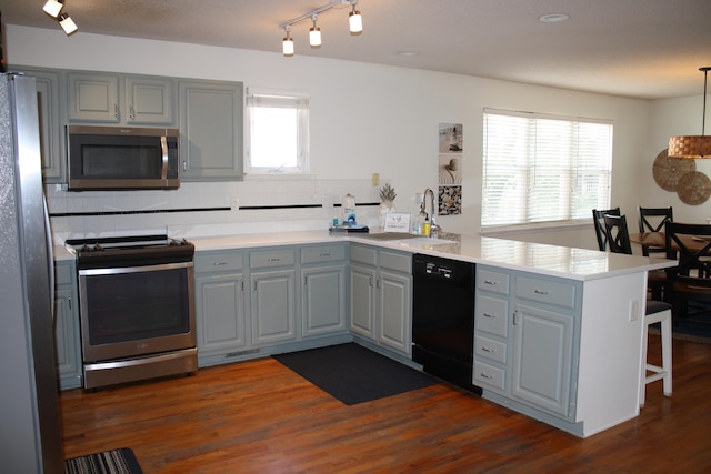 kitchen featuring plenty of natural light, stainless steel appliances, kitchen peninsula, and dark hardwood / wood-style floors