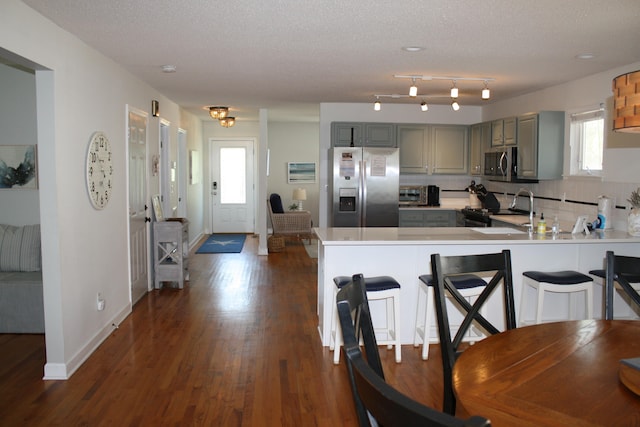 kitchen with stainless steel appliances, a textured ceiling, dark hardwood / wood-style floors, and gray cabinets