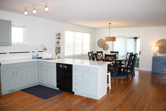 kitchen with black dishwasher, a textured ceiling, dark hardwood / wood-style flooring, kitchen peninsula, and decorative light fixtures