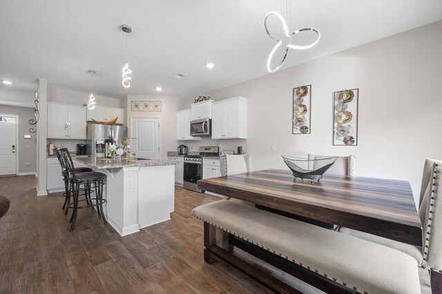 225 N Light Way, Summerville, SC 29486 - kitchen featuring appliances with stainless steel finishes, dark wood-style flooring, a breakfast bar, a center island with sink, and recessed lighting