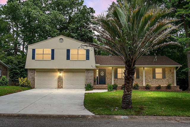 tri-level home featuring concrete driveway, brick siding, a yard, and an attached garage