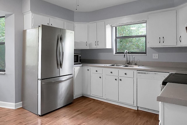 kitchen featuring a sink, appliances with stainless steel finishes, light wood-style flooring, and a healthy amount of sunlight
