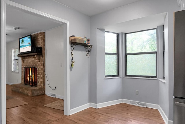 interior space featuring baseboards, a fireplace, wood finished floors, and visible vents