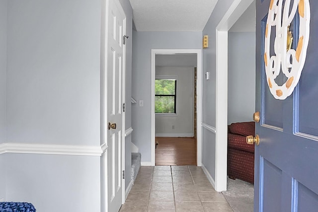 interior space with baseboards, a textured ceiling, and light tile patterned flooring
