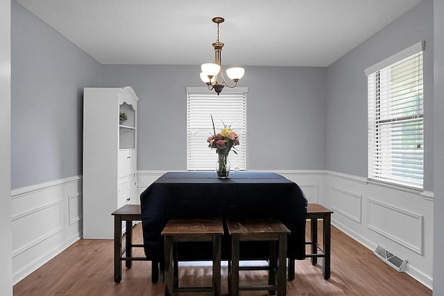 dining space with visible vents, wainscoting, and wood finished floors