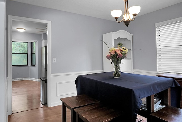 dining area with wainscoting, wood finished floors, and a notable chandelier
