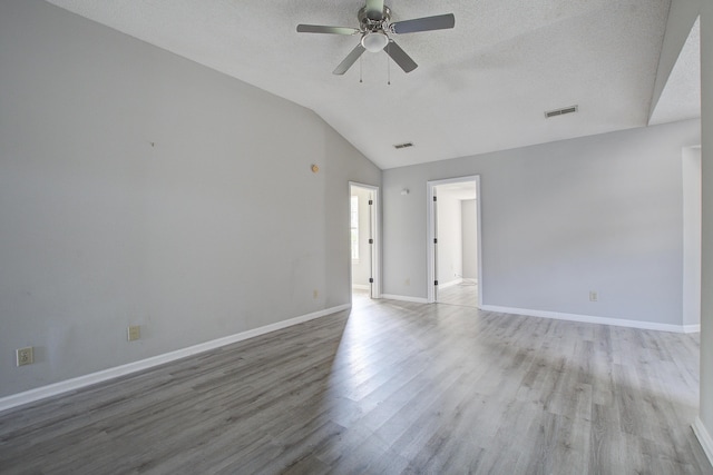 spare room with visible vents, vaulted ceiling, wood finished floors, and ceiling fan