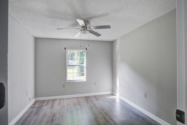 empty room featuring baseboards, a ceiling fan, wood finished floors, and a textured ceiling