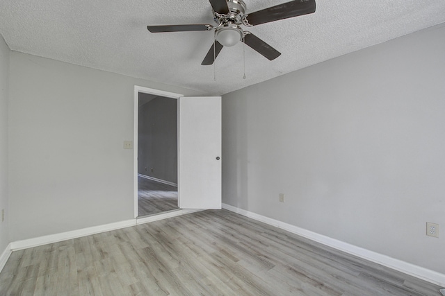empty room featuring wood finished floors, a textured ceiling, baseboards, and ceiling fan