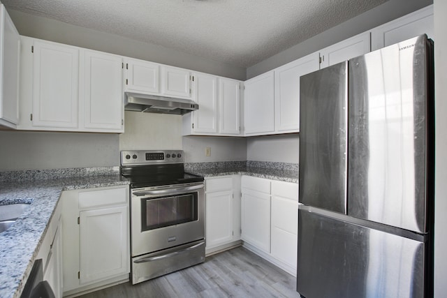 kitchen with stainless steel appliances, under cabinet range hood, a textured ceiling, and light wood-style floors