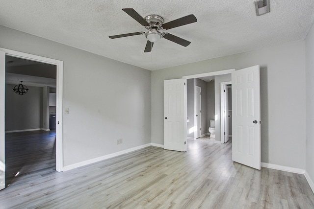 unfurnished bedroom featuring a textured ceiling, wood finished floors, visible vents, and baseboards