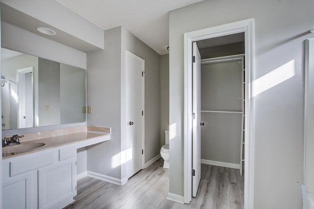 bathroom featuring baseboards, wood finished floors, vanity, and toilet