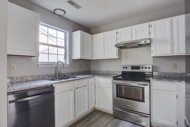 kitchen featuring a sink, a textured ceiling, visible vents, under cabinet range hood, and appliances with stainless steel finishes