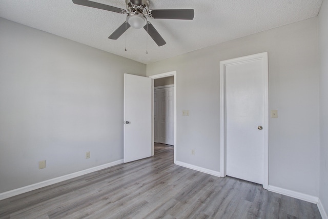 unfurnished bedroom with baseboards, wood finished floors, a textured ceiling, and ceiling fan