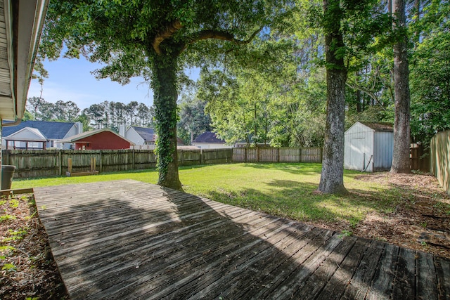 wooden deck with a yard, an outbuilding, a shed, and a fenced backyard