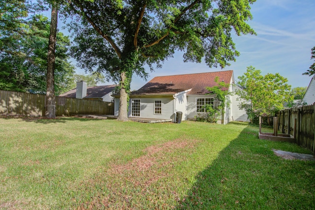 rear view of property with a lawn and a fenced backyard