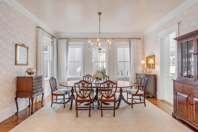 dining space with crown molding, a chandelier, and light hardwood / wood-style flooring