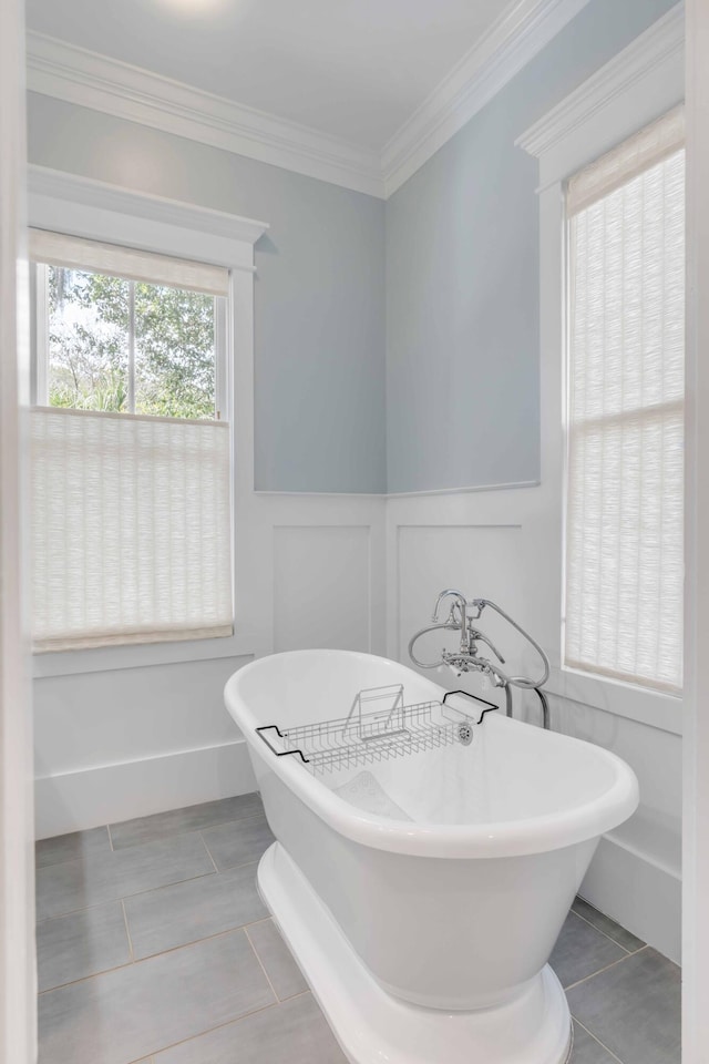 bathroom featuring tile patterned flooring, crown molding, and a tub to relax in