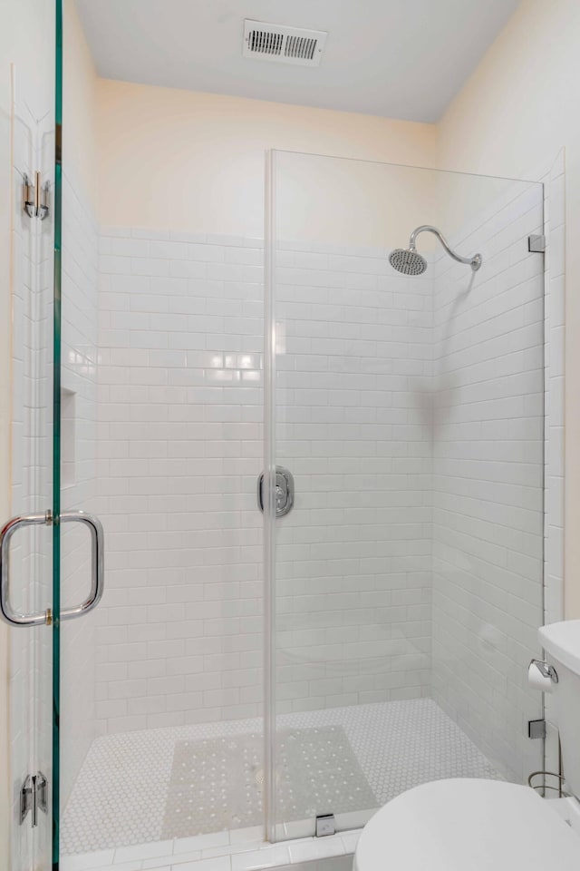 bathroom featuring a shower with shower door and toilet