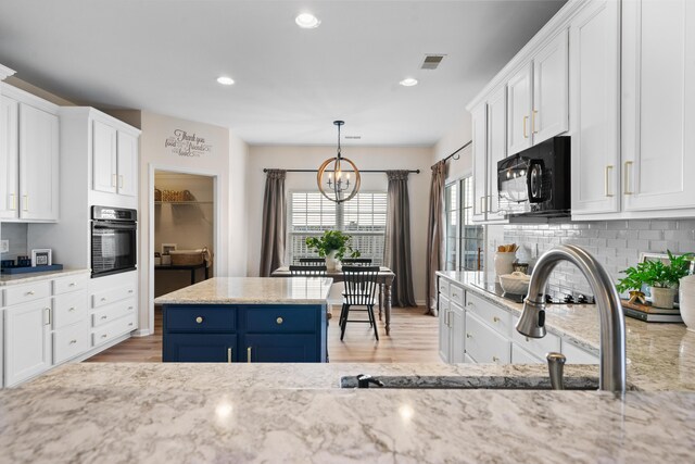 kitchen with black appliances, decorative light fixtures, light hardwood / wood-style floors, and white cabinets