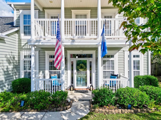 property entrance with covered porch and a balcony