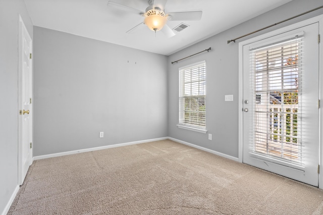 unfurnished room with a wealth of natural light, light carpet, and ceiling fan