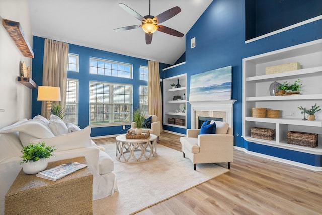 living room featuring high vaulted ceiling, built in features, wood-type flooring, and ceiling fan