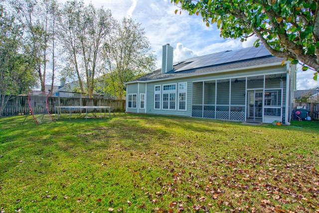 back of house with a sunroom, a yard, and a trampoline