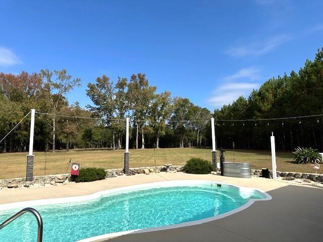 outdoor pool featuring a lawn