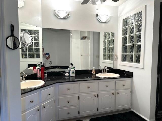 full bathroom with double vanity, a ceiling fan, and a sink