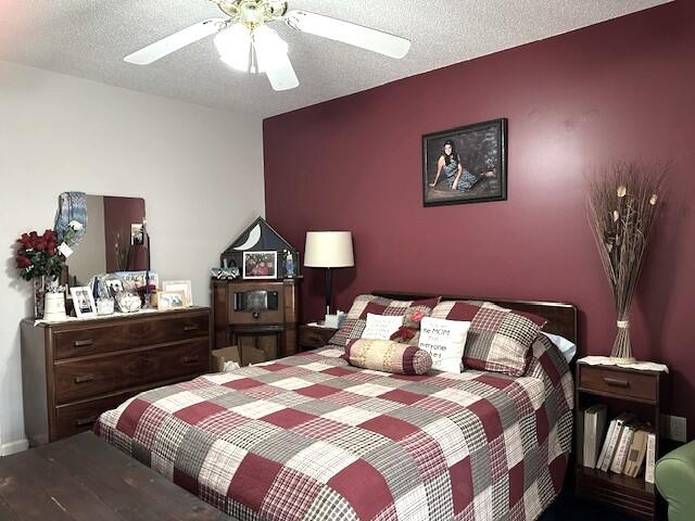 bedroom with a textured ceiling, wood-type flooring, and ceiling fan