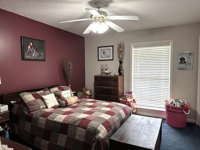 bedroom with a ceiling fan, carpet floors, and a textured ceiling