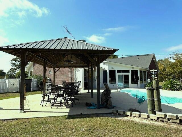 exterior space with a sunroom, a fenced in pool, a ceiling fan, a gazebo, and fence