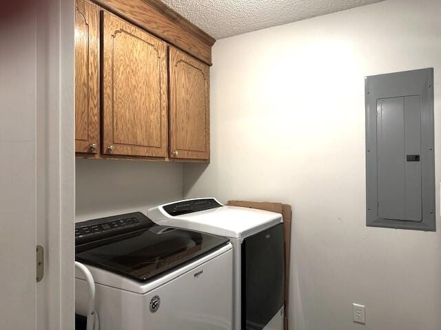 clothes washing area with independent washer and dryer, a textured ceiling, cabinets, and electric panel