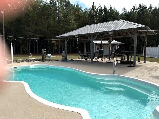 outdoor pool featuring a patio, fence, and a gazebo