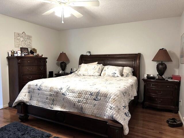 bedroom with a textured ceiling, dark wood-type flooring, and ceiling fan